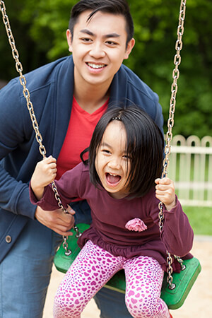 Asian Dad pushes Daughter on Swings