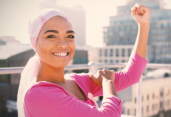 A young woman showing off her bicep to signify that she has beaten breast cancer. 